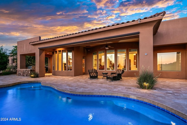 pool at dusk featuring a patio area and ceiling fan