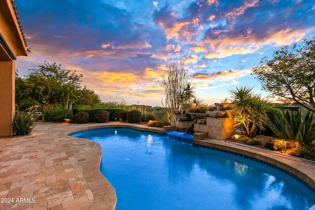 pool at dusk featuring a patio area