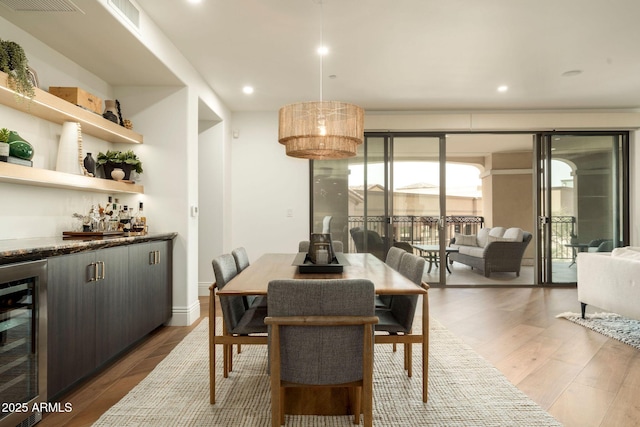 dining area featuring beverage cooler, visible vents, wood finished floors, a bar, and recessed lighting