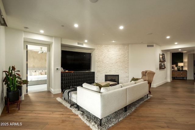 living area featuring recessed lighting, visible vents, a stone fireplace, and wood finished floors