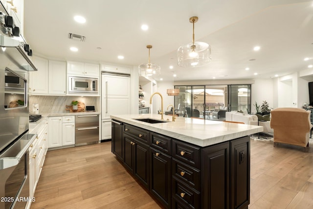 kitchen with built in appliances, a sink, visible vents, white cabinetry, and light wood-type flooring