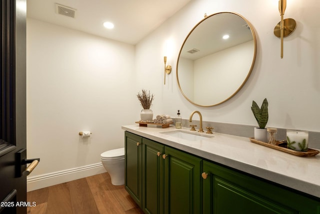 bathroom featuring visible vents, toilet, vanity, wood finished floors, and baseboards