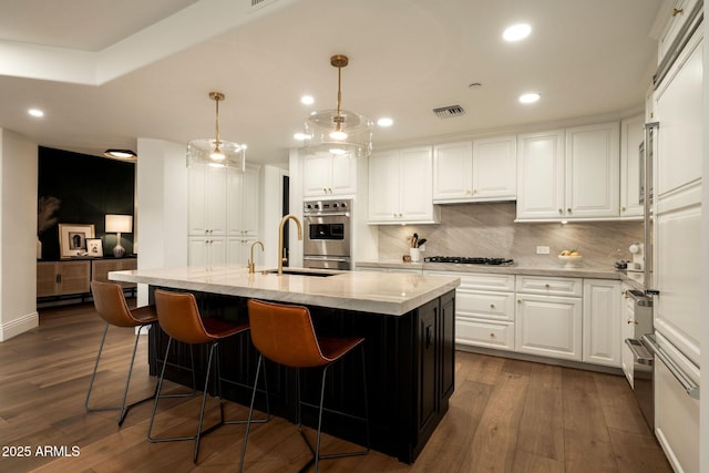 kitchen featuring gas cooktop, dark wood-style flooring, white cabinetry, light stone countertops, and tasteful backsplash