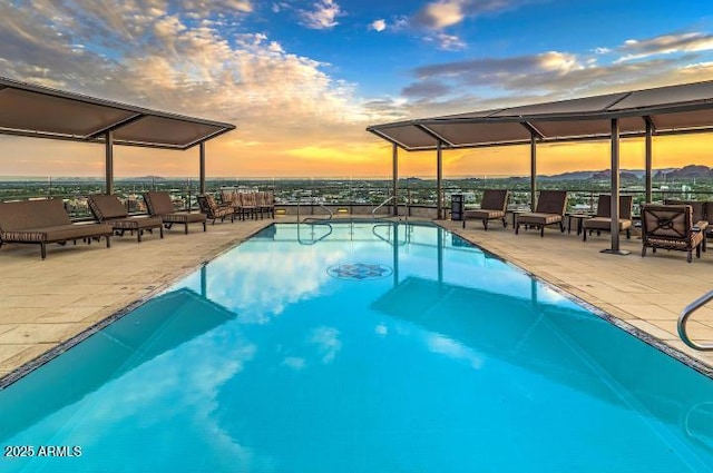 pool at dusk with a lanai, a community pool, and a patio