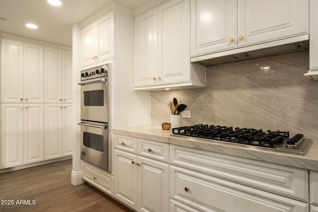 kitchen featuring appliances with stainless steel finishes, white cabinetry, under cabinet range hood, and wood finished floors