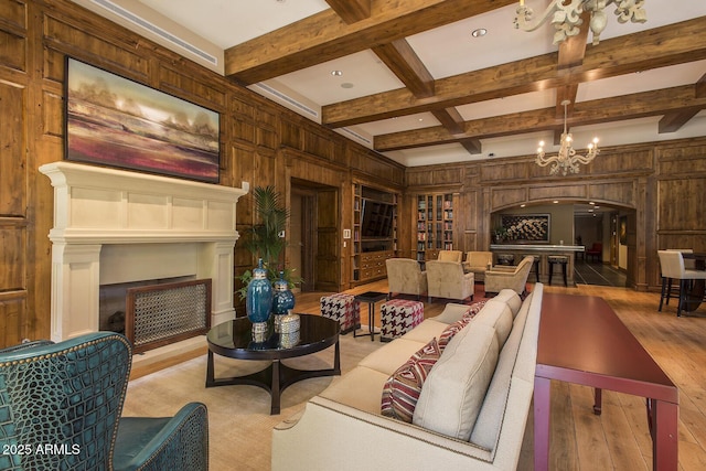 living room featuring arched walkways, a fireplace, wooden walls, and beamed ceiling