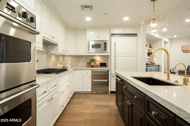 kitchen with visible vents, white cabinets, stainless steel appliances, light wood-style floors, and a sink