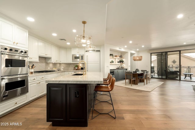 kitchen featuring visible vents, white cabinetry, stainless steel appliances, and wood finished floors