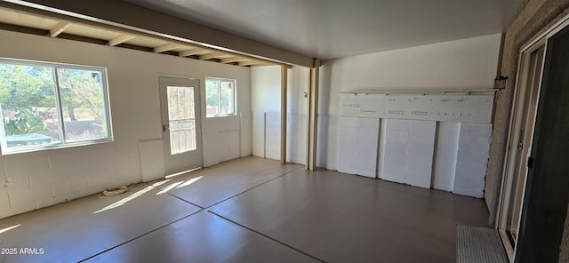 foyer featuring finished concrete floors and beam ceiling