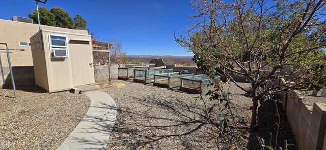 view of yard with a garden, an outdoor structure, a storage unit, and fence