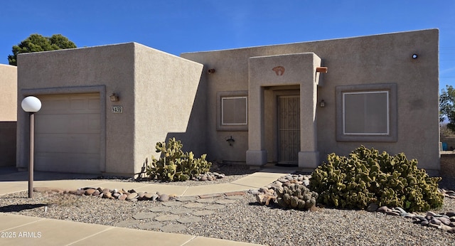 pueblo-style house featuring a garage and stucco siding