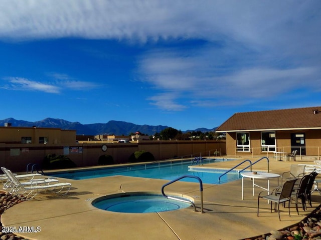 pool featuring a patio area, a hot tub, fence, and a mountain view