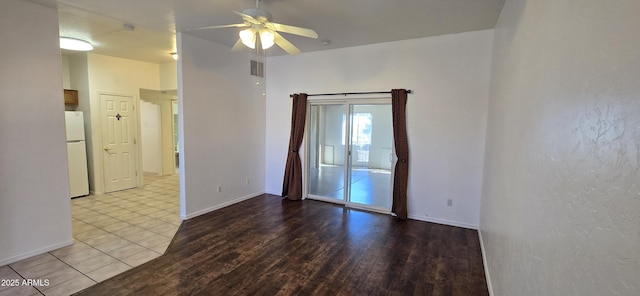 empty room featuring baseboards, light wood finished floors, visible vents, and a ceiling fan