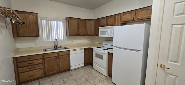 kitchen with light tile patterned floors, light countertops, white appliances, and a sink