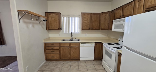 kitchen with light tile patterned floors, light countertops, white appliances, and a sink