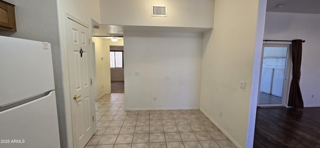 interior space featuring freestanding refrigerator, visible vents, baseboards, and light tile patterned flooring