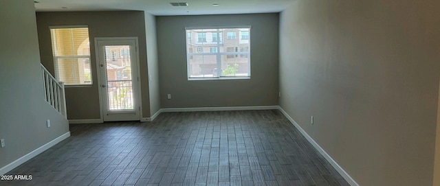 unfurnished room featuring plenty of natural light and dark wood-type flooring