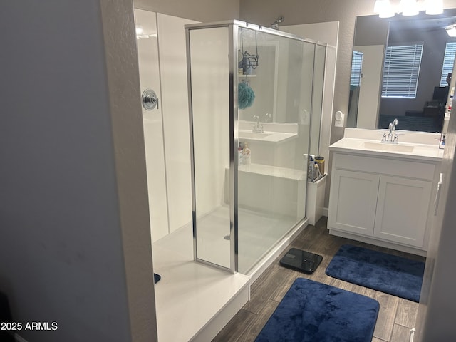 full bath with connected bathroom, wood finish floors, a sink, and a shower stall