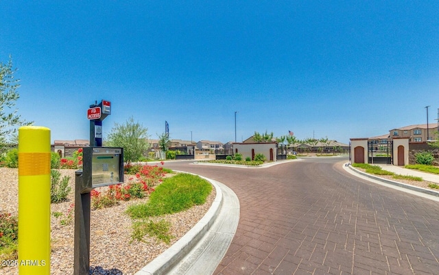 view of road featuring curbs, a gated entry, a gate, and a residential view