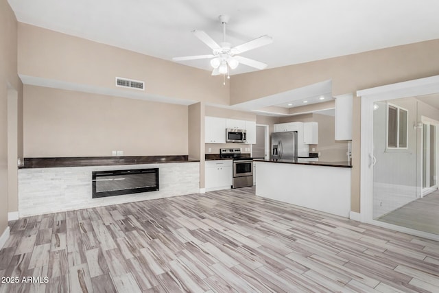 kitchen featuring dark countertops, visible vents, open floor plan, appliances with stainless steel finishes, and white cabinetry