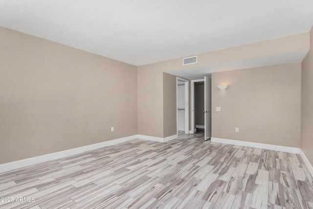 empty room with visible vents, baseboards, and light wood finished floors