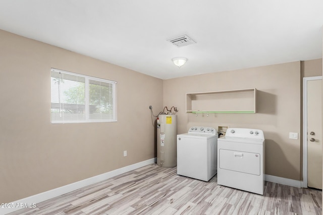 clothes washing area with washer and dryer, baseboards, visible vents, and electric water heater