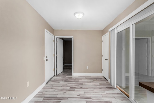 interior space with light wood-style floors, baseboards, and access to outside