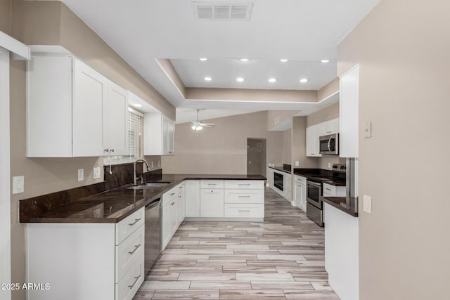 kitchen featuring visible vents, a sink, dark countertops, stainless steel appliances, and ceiling fan