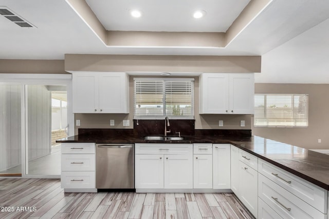 kitchen featuring a sink, visible vents, dark countertops, and dishwasher