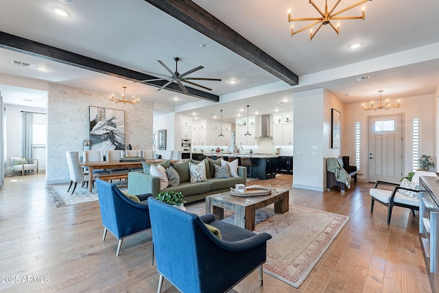 living room with light wood-type flooring, visible vents, beamed ceiling, and an inviting chandelier