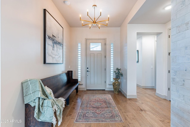 entryway featuring light wood-style floors, baseboards, and a notable chandelier