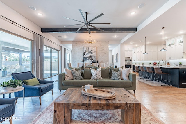 living room featuring light wood-type flooring, beam ceiling, and an inviting chandelier