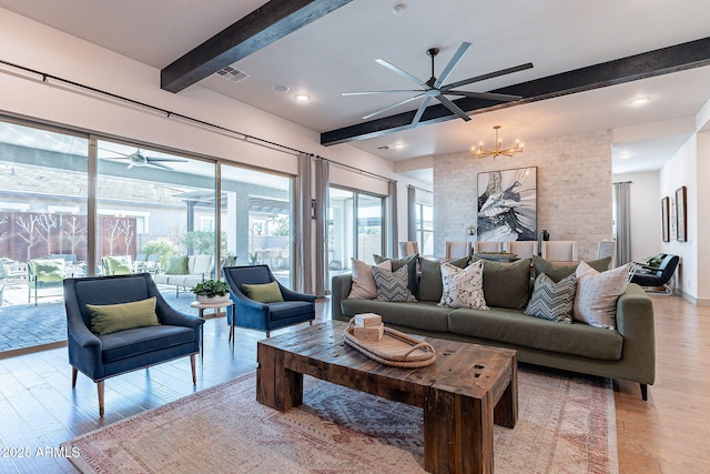 living area featuring light wood-type flooring, visible vents, beamed ceiling, and ceiling fan with notable chandelier