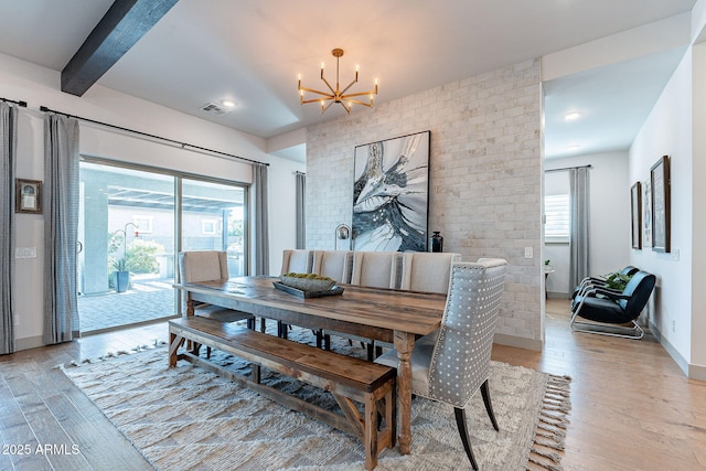 dining space with a chandelier, visible vents, baseboards, light wood-type flooring, and beam ceiling