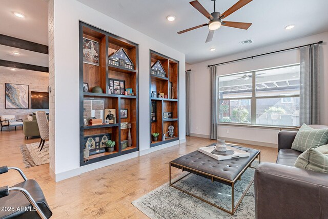 living area with baseboards, built in shelves, visible vents, and wood finished floors