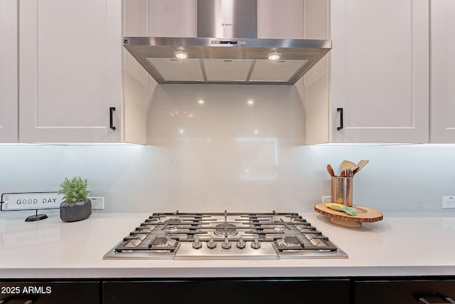 kitchen featuring stainless steel gas stovetop, light countertops, white cabinets, and range hood