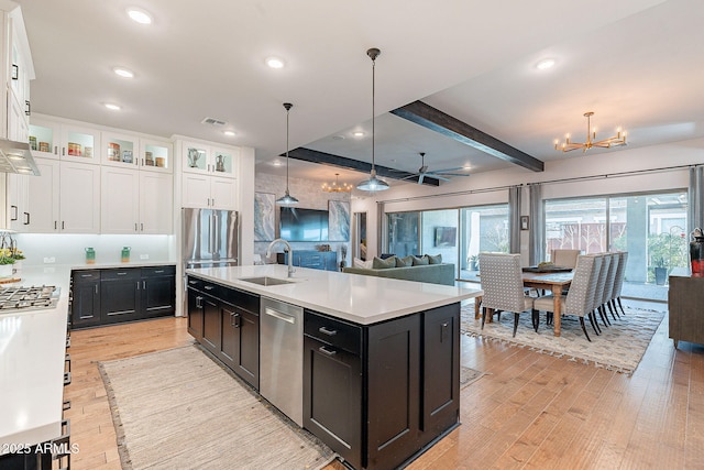 kitchen featuring stainless steel appliances, light wood finished floors, a sink, and white cabinetry