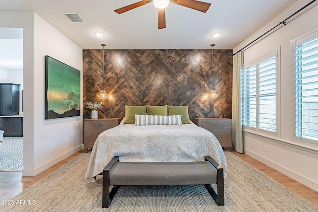 bedroom featuring light wood-style floors, baseboards, an accent wall, and visible vents