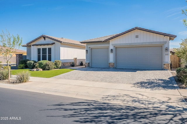 view of front facade with an outbuilding, a tiled roof, decorative driveway, and fence