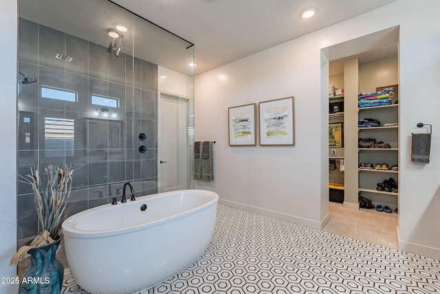 bathroom with a soaking tub, tiled shower, a spacious closet, and baseboards