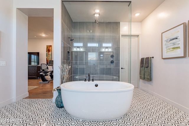 bathroom featuring a freestanding tub, a tile shower, baseboards, and tile patterned floors