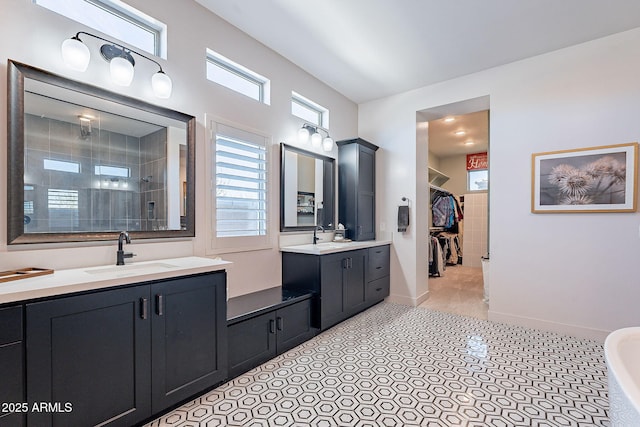 full bathroom with baseboards, a sink, tile patterned flooring, a tile shower, and two vanities