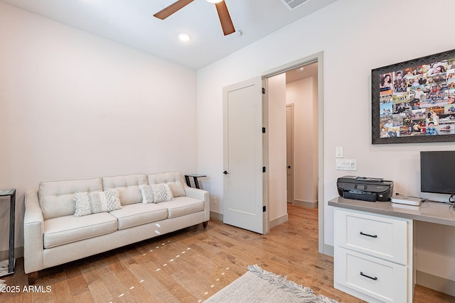 living area with light wood-style flooring, visible vents, baseboards, and a ceiling fan