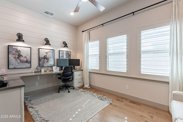 office area featuring a ceiling fan, wood finished floors, visible vents, and baseboards