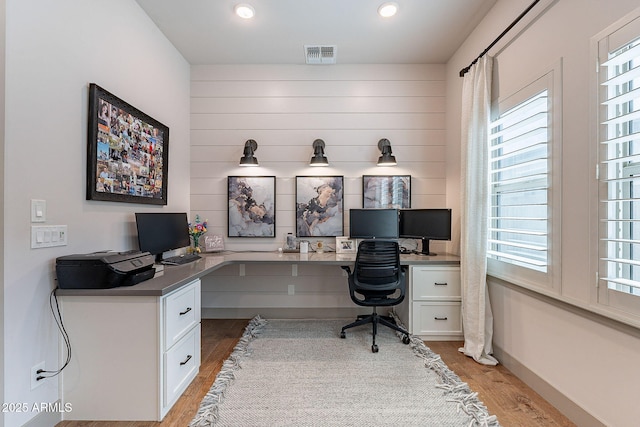 office area featuring light wood finished floors, baseboards, visible vents, built in desk, and recessed lighting