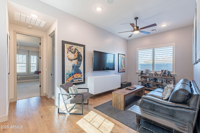 living area featuring ceiling fan, light wood finished floors, visible vents, and baseboards