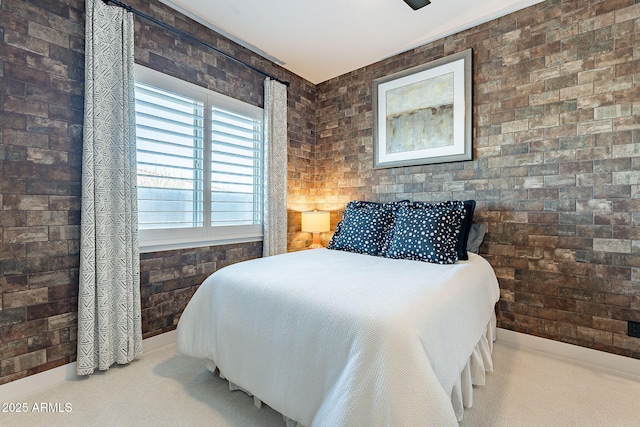 carpeted bedroom featuring baseboards and brick wall