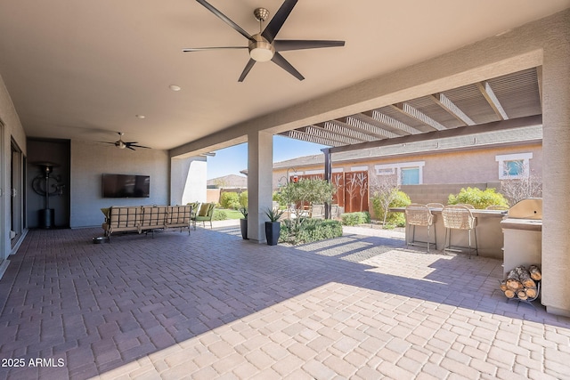 view of patio featuring ceiling fan, fence, and an outdoor kitchen