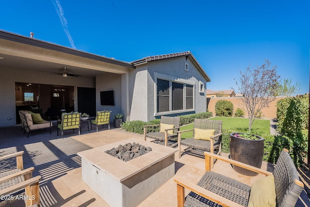 view of patio featuring a ceiling fan, an outdoor living space with a fire pit, and fence