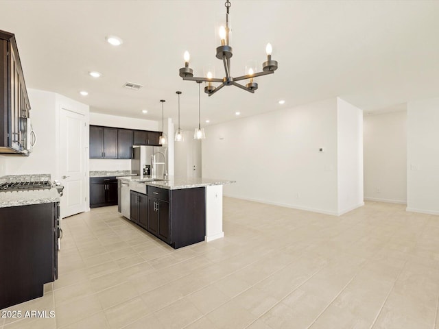 kitchen featuring stainless steel appliances, hanging light fixtures, a chandelier, a center island with sink, and dark brown cabinets